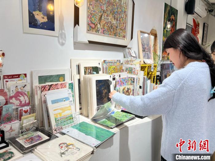 圖為藝術(shù)品商店內(nèi)，顧客挑選插畫作品?！＄婌?攝