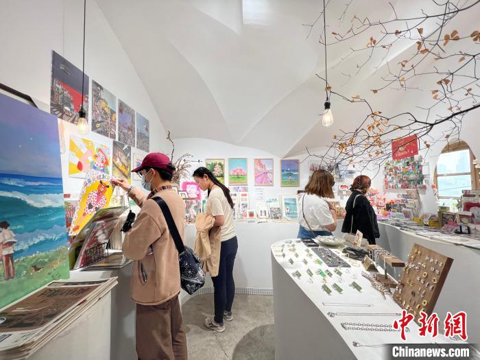 圖為藝術(shù)品商店內(nèi)，顧客挑選插畫作品?！＄婌?攝