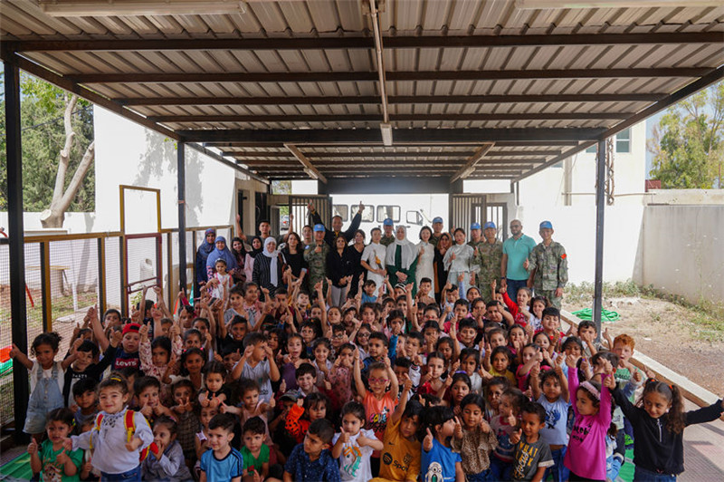當地時間5月30日，黎巴嫩南部庫雷拉公立小學，“六一”國際兒童節(jié)前夕，中國第21批赴黎維和多功能工兵分隊官兵看望慰問學校師生，并開展文化交流活動，圖為我維和官兵同師生合影。李竹林攝