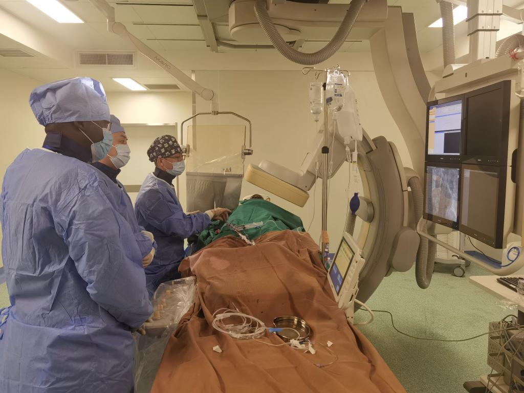 中國第29批援幾內亞醫(yī)療隊隊員、首都醫(yī)科大學附屬北京天壇醫(yī)院心內科副主任醫(yī)師王汝朋（右一）正在給患者做手術。（北京天壇醫(yī)院供圖）
