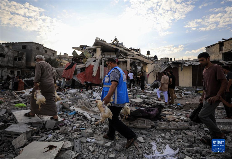 10月27日，在加沙地帶南部城市汗尤尼斯，人們經(jīng)過以軍襲擊后的房屋廢墟。