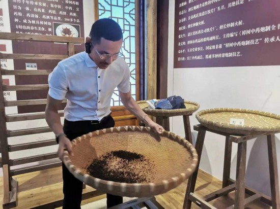 2023“一帶一路”媒體合作論壇聯(lián)合采訪團團員在非遺文化展示館體驗中藥炮制技藝。（本報記者 黃超攝）