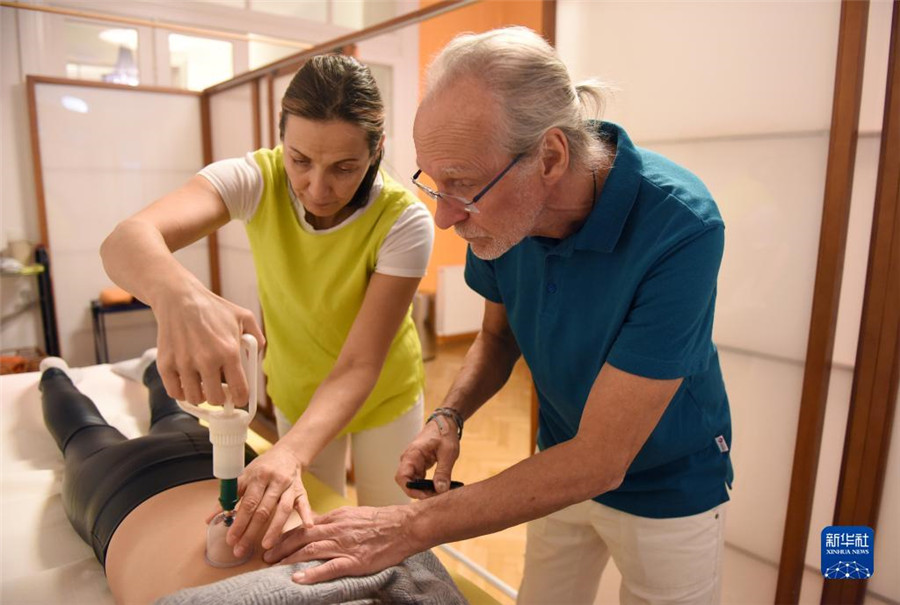 12月12日，在奧地利維也納，科格勒醫(yī)生（右）和助手在為病人進(jìn)行拔罐治療。新華社記者 賀燦鈴 攝