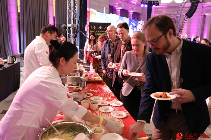 當(dāng)?shù)貢r(shí)間3月7日晚，華盛頓聯(lián)合車站廣場舉行駐美使團(tuán)“使館主廚挑戰(zhàn)賽”。圖為當(dāng)?shù)孛癖娫谥袊古_(tái)前體驗(yàn)中國美食。人民網(wǎng)記者 李志偉攝