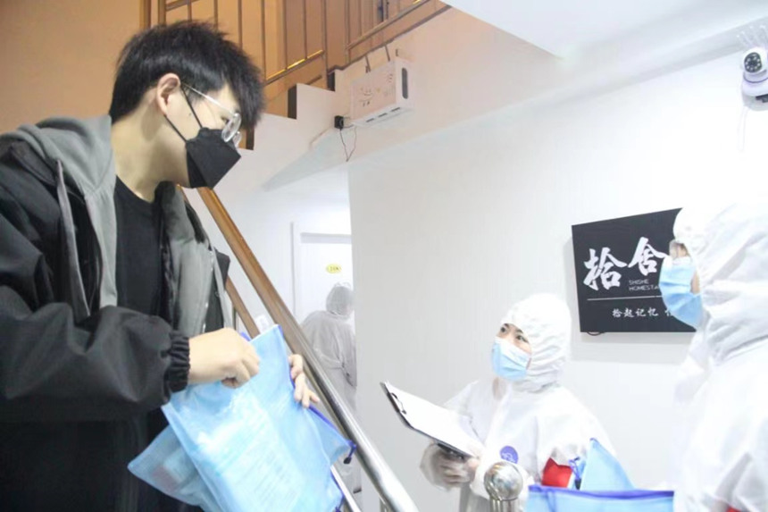 社區(qū)工作人員和志愿者身穿防護服上門送馬應龍大健康防疫包。徐帥攝