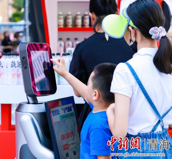 圖為一名小朋友正在和機器人“志愿者”進行互動。 沐聞 攝