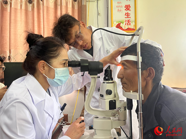 王紅英（左）和團隊成員為達熱村村民檢查眼睛。人民網(wǎng)記者 杜燕飛攝