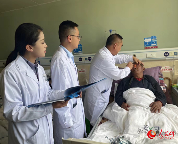董光明（左三）帶領醫(yī)生對患者進行術前檢查。人民網(wǎng)記者 杜燕飛攝