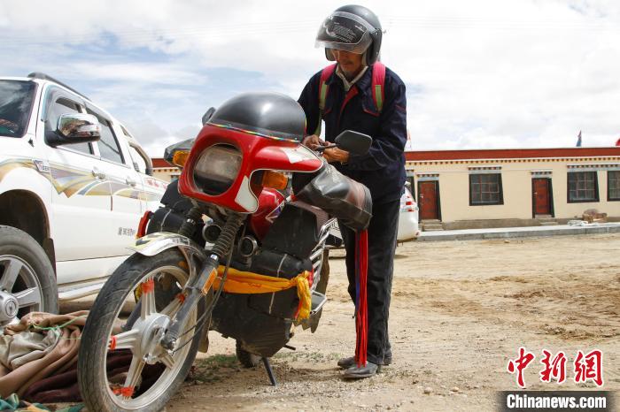 圖為白瑪準(zhǔn)備騎摩托車巡湖?！≮w朗 攝