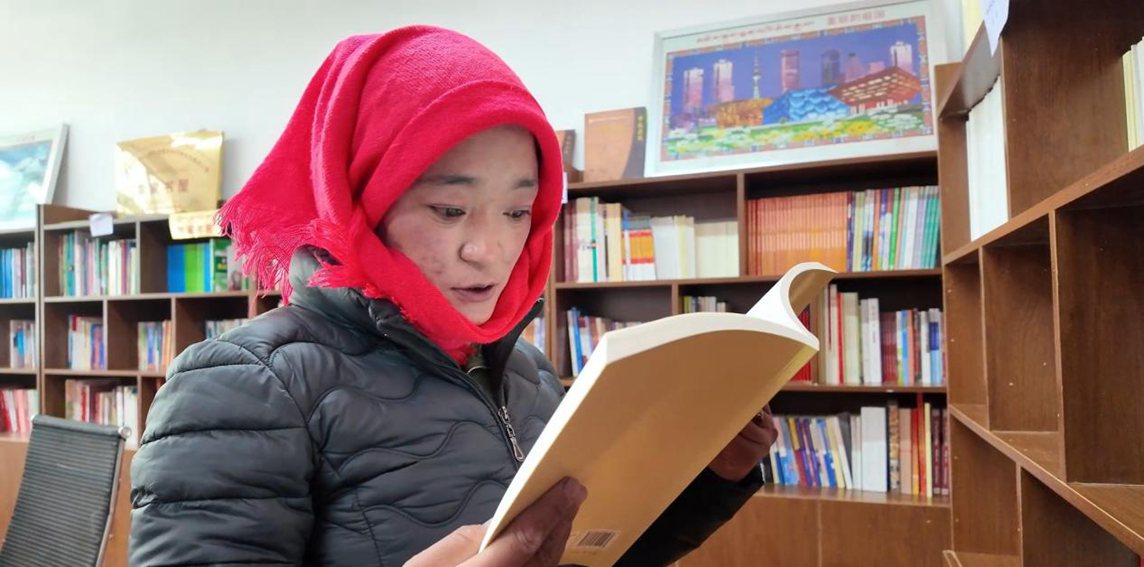 一名婦女正在認真閱讀書籍。申扎縣融媒體中心供圖
