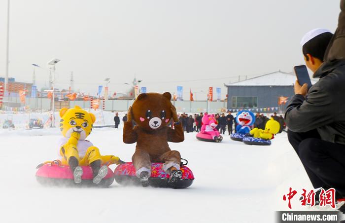 圖為臨夏市南龍鎮(zhèn)馬家莊村舉辦的鄉(xiāng)村文化旅游節(jié)上，游客穿著卡通服裝在體驗雪上飛碟項目。近年來，臨夏州形成了“春賞花、夏避暑、秋摘果、冬玩雪”的全季節(jié)旅游產(chǎn)品體系。(資料圖) 高展 攝