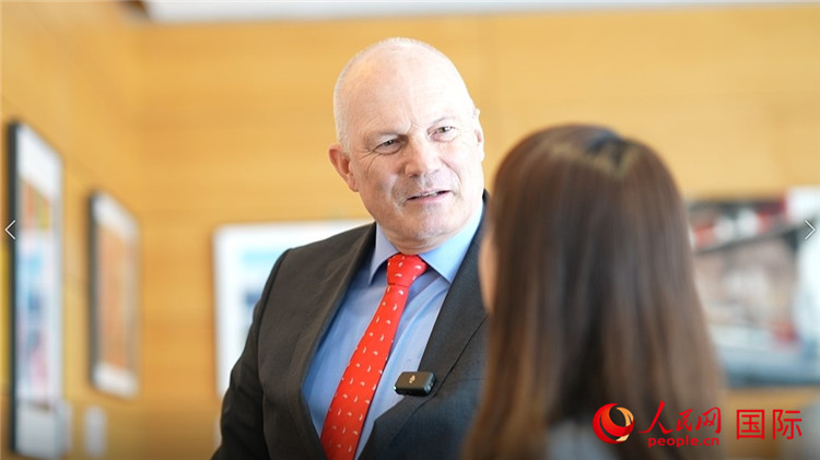 瑞士駐華大使白瑞誼介紹使館內(nèi)陳列的照片。人民網(wǎng) 彭昱凱攝