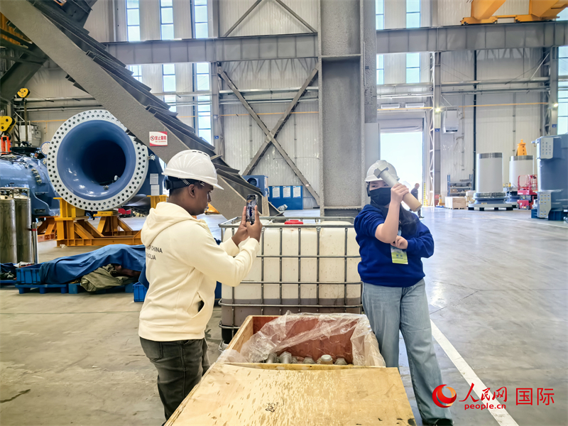 外媒記者掂量廠房?jī)?nèi)的巨型螺栓。人民網(wǎng) 楊春燕攝