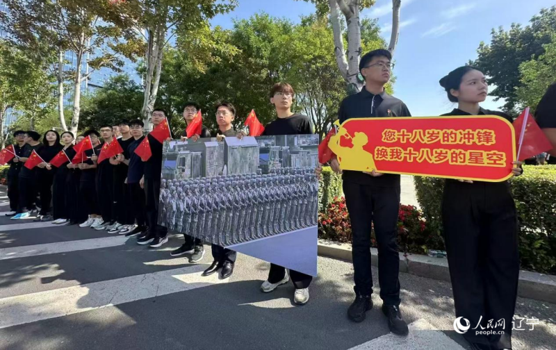 沈陽市人民廣場上，大學(xué)生們手持閱兵的圖片，告慰英烈。人民網(wǎng)記者 周頌雪攝