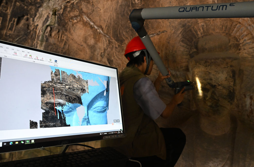 2025年4月9日，武漢大學(xué)文化遺產(chǎn)智能計算實(shí)驗(yàn)室團(tuán)隊成員在魏字洞使用關(guān)節(jié)臂掃描儀對佛像進(jìn)行數(shù)字化掃描。圖片來源新華社