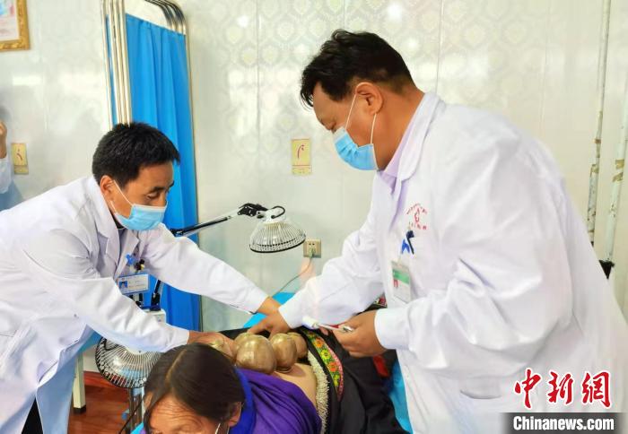 圖為看照加手把手帶徒弟加老(左一)進(jìn)行拔罐療法?！堟?攝