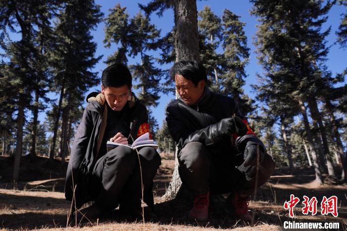 圖為桑杰加(左)和同事記錄巡查結(jié)果。　馬銘言 攝