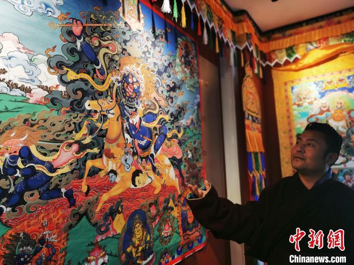 圖為久美尖措展示唐卡作品?！?zhí)砀?攝