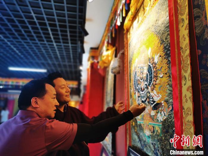 圖為久美尖措展示唐卡作品?！?zhí)砀?攝