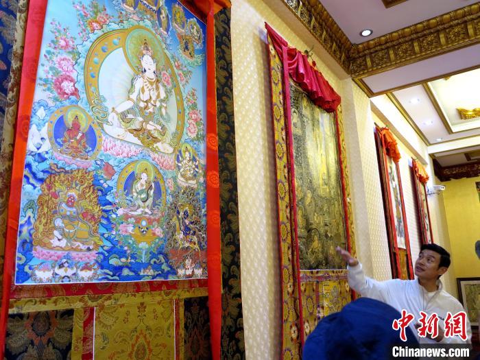 圖為完德尖措展示熱貢龍樹畫苑內(nèi)的唐卡。　張?zhí)砀?攝
