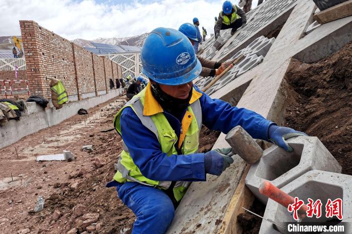 圖為光伏發(fā)電項(xiàng)目施工區(qū)工人在護(hù)坡鋪設(shè)空心磚?！±铍h 攝