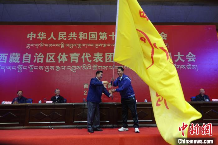 西藏自治區(qū)副主席甲熱·洛桑丹增授代表團團旗，西藏自治區(qū)體育局局長尼瑪次仁接旗?！∪轿木?攝
