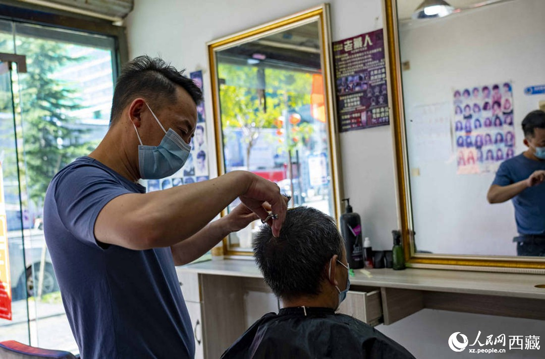 理發(fā)店老板為顧客理發(fā)。次仁羅布 攝