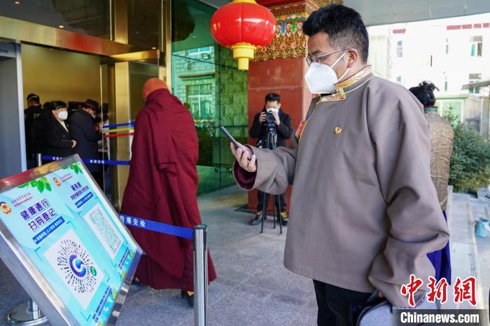 圖為政協(xié)委員掃場所碼進入會場?！〗w波 攝