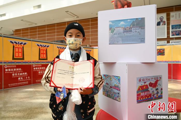 圖為一名獲獎(jiǎng)學(xué)生與自己的繪畫(huà)作品合影?！≮w朗 攝
