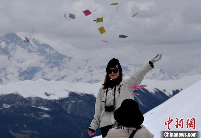 圖為5月14日，游客在西藏林芝色季拉山觀景臺拋灑“隆達”(風(fēng)馬旗，藏族民眾的一種祈福方式)?！±盍?攝