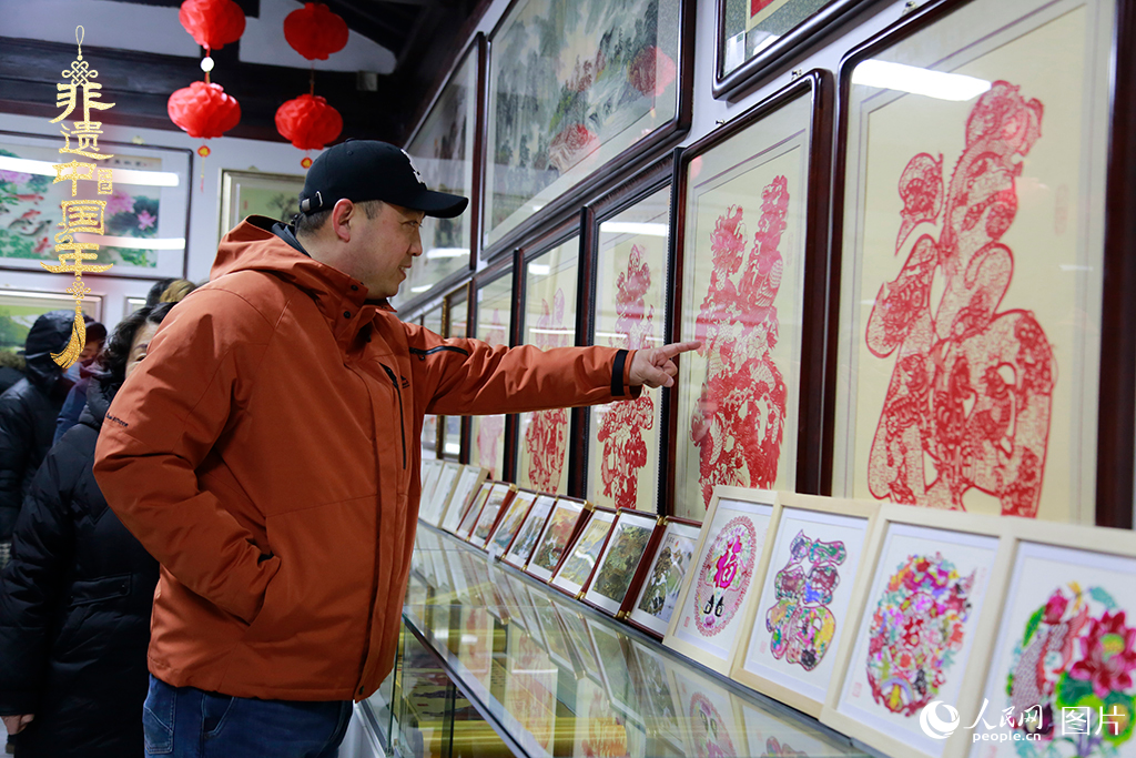 2025年1月23日，游客在天津楊柳青古鎮(zhèn)欣賞傳統(tǒng)剪紙作品，感受指尖上的古老藝術。人民網(wǎng)記者 崔新耀攝