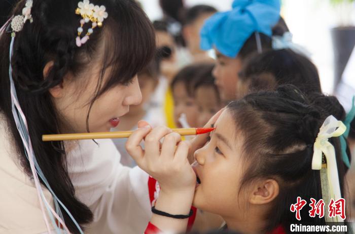 圖為老師在孩子們額頭上點(diǎn)上雄黃，驅(qū)邪辟禍?！《^生 攝